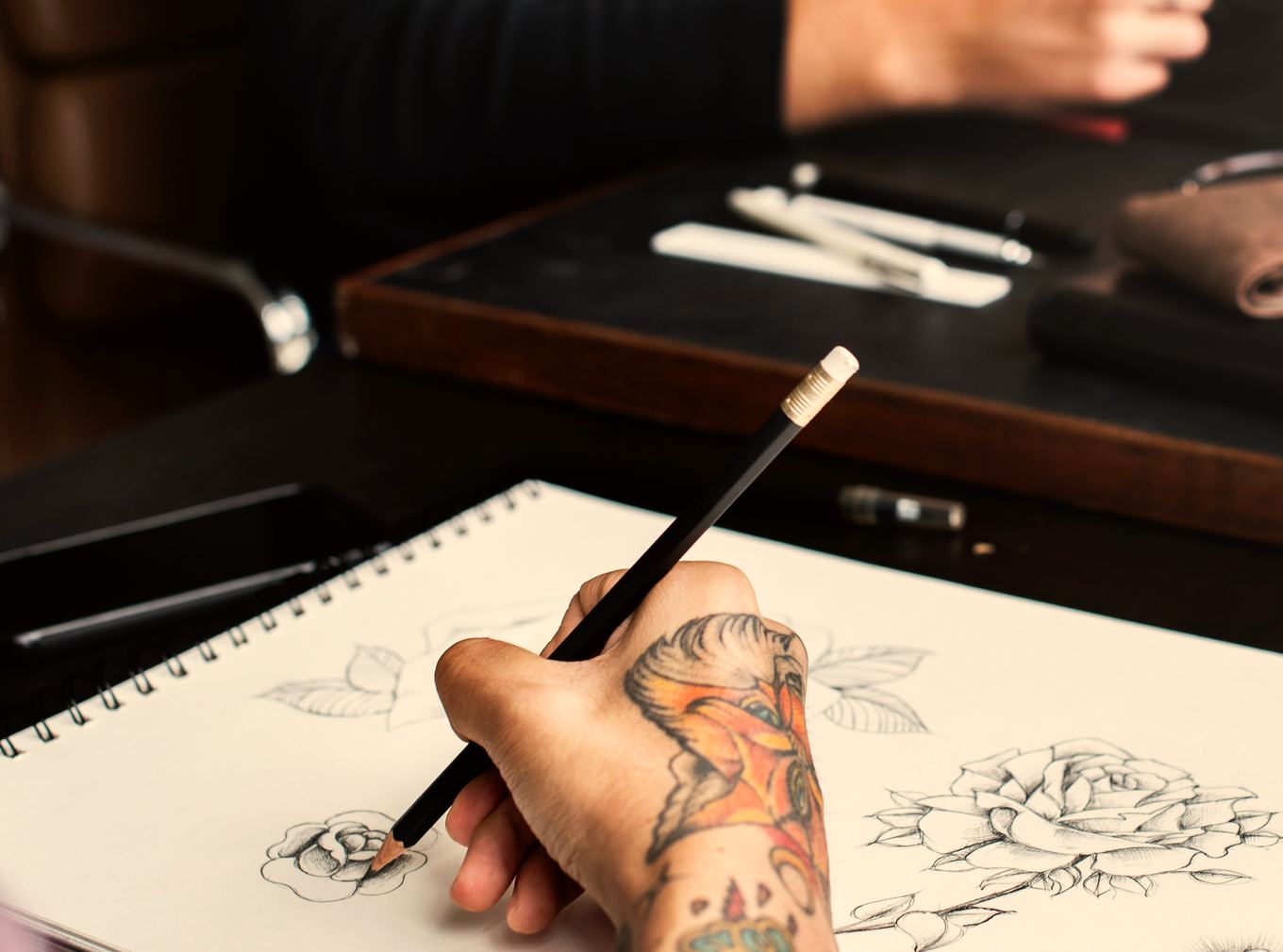Tattooed artist hand drawing a branding sketch